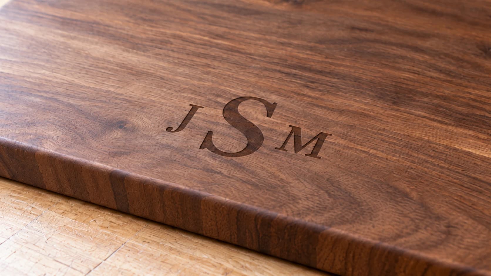 Vue rapprochée de la même planche en noyer montrant une gravure J-S-M brune et peu profonde suivant un fil du bois continu