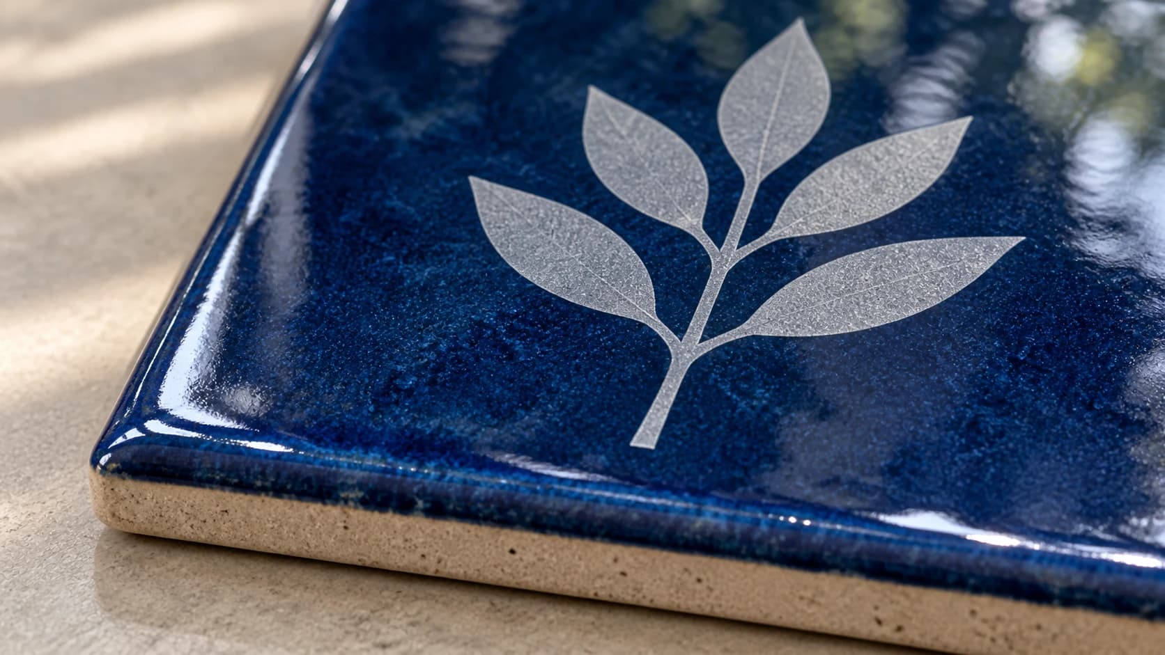 Matte leaf mark within a glossy blue ceramic tile surface