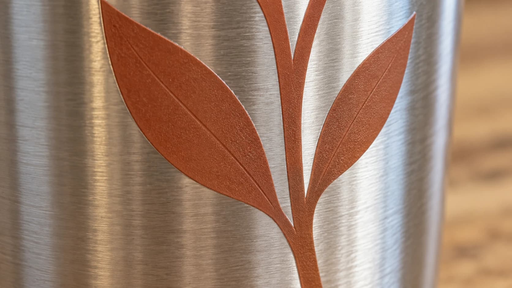 Folhas de vinil terracota acompanhando a curva de um copo térmico de aço inoxidável